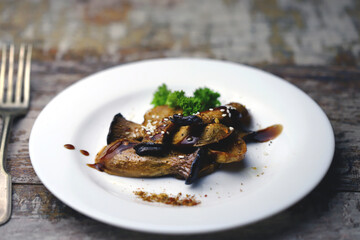 Close-up. Selective focus. Fried eringi mushrooms, served on a white plate.