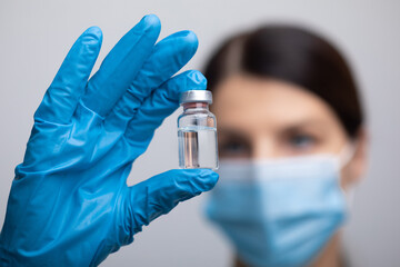 Doctor scientist with protective gloves and face mask holding vaccine medicine dose