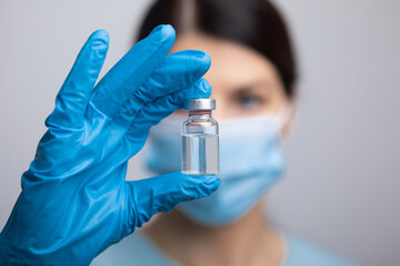 Fototapeta premium Doctor scientist with protective gloves and face mask holding vaccine medicine dose