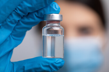 Doctor scientist with protective gloves and face mask holding vaccine medicine dose