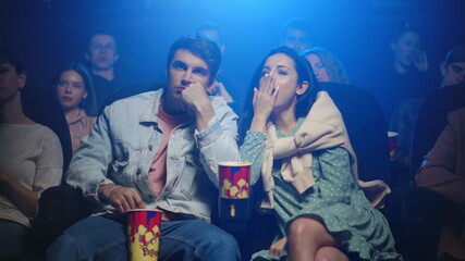Sleepy woman yawning in cinema. Tired couple watching film in movie theater.