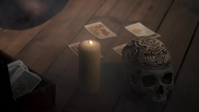 Scene of fortune-teller forecasting fate with tarot cards. Woman placing cards in order as mystic rite. Halloween divination in spooky esoteric atmosphere with candle and skull on background.