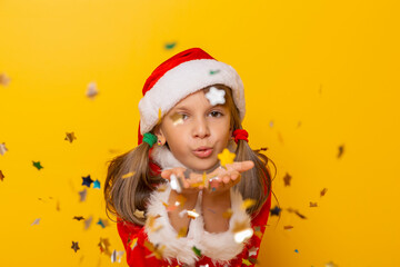Fototapeta na wymiar Little girl wearing Santa costume blowing away colorful confetti