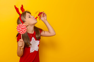 Child wearing costume reindeer antlers blowing a party whistle