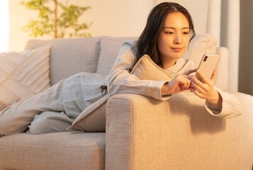 リラックスして携帯を触るアジア人女性