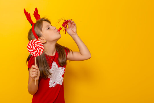 Child Wearing Costume Reindeer Antlers Blowing A Party Whistle