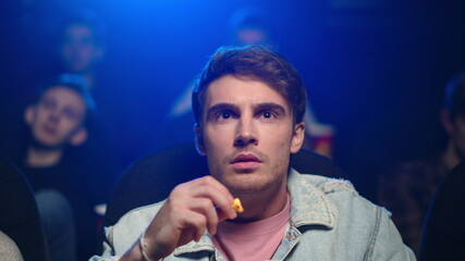 Scared man watching horror in cinema. Guy screaming in movie theater.