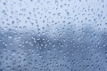 Melting snow on the glass, drops of water condensation on the window, and transparent glass of the window in cold winter, winter landscape outside the window, close-up.