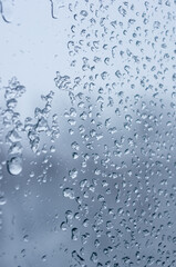 Melting snow on the glass, drops of water condensation on the window, and transparent glass of the window in cold winter, winter landscape outside the window, close-up.
