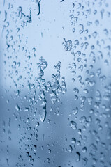 Melting snow on the glass, drops of water condensation on the window, and transparent glass of the window in cold winter, winter landscape outside the window, close-up.