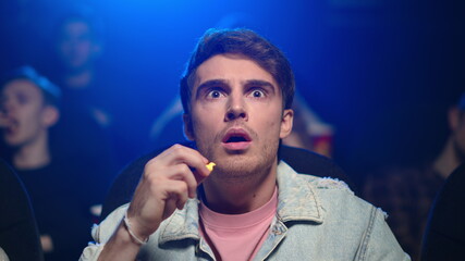 Worried man spending evening in movie theater. Guy watching movie in cinema.