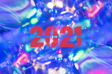 Christmas background-garlands with colorful lights on a decorated Christmas tree, bokeh, Happy New Year 2021 colored symbol and text in trendy flatten style design for seasonal holidays flyers