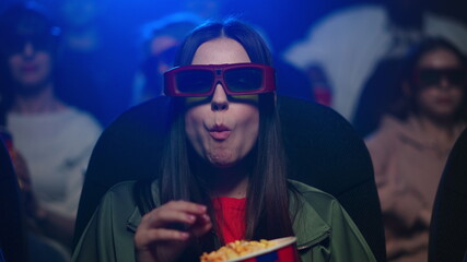 Closeup scared woman watching movie in cinema. Girl in 3d glasses eating popcorn