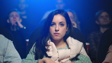 Focused woman watching scary movie. Shocked girl startling in movie theater.