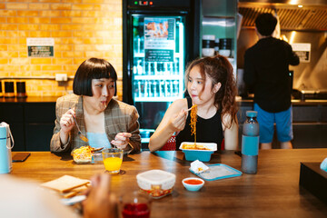 Asian business people take a break having lunch together in kitchen.