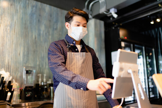 Asian Barista Man Wearing Mask Working On Digital Menu In Laptop.