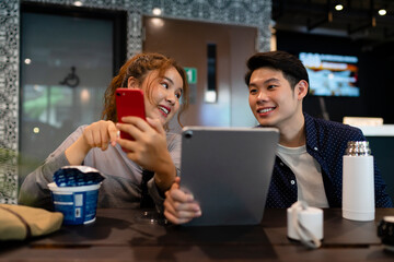 Couple looking at digital laptop at cafe bar.