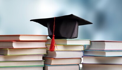 Stack school books with black graduation hat