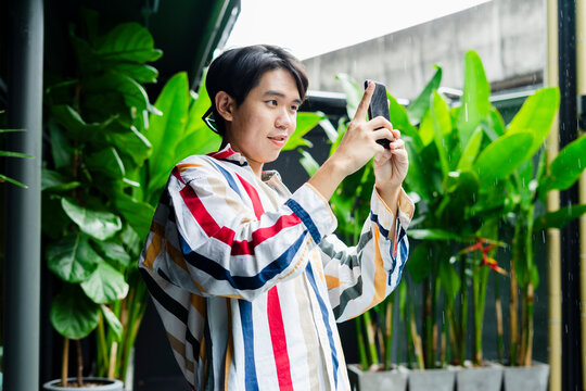 Asian man taking photo with smartphone in hotel.