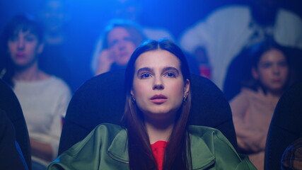 Closeup emotional woman watching sentimental film in movie theater.
