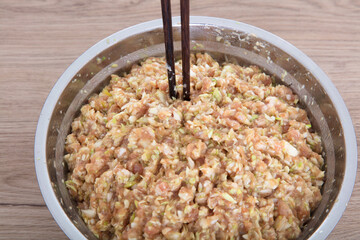 The steel pot is filled with prepared pork and green onion dumplings
