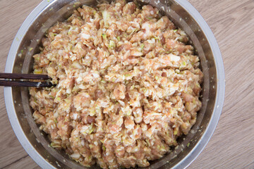 The steel pot is filled with prepared pork and green onion dumplings