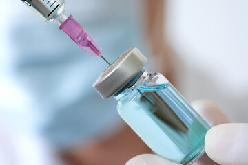 doctor's hand holds a syringe and a blue vaccine bottle at the hospital. Health and medical concepts.