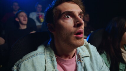 Expressive man watching film indoor. Shocked guy surprising in cinema.