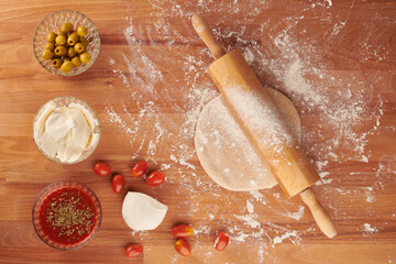 Making italian pizza step by step: small dough with a rolling pin