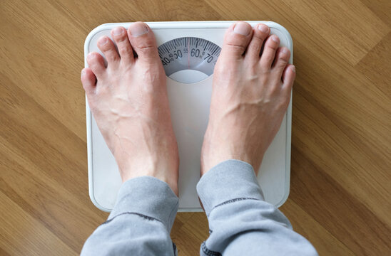 A woman walks in her house and she walks on the scale to Check her body weight on the manual weight scale. Concept of healthy lifestyle and sport