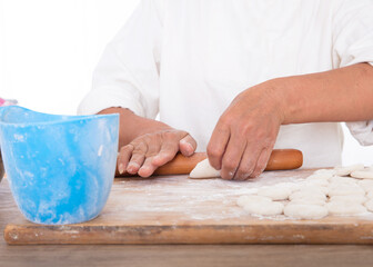 Chinese people are rolling dumpling wrappers with a rolling pin