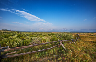 Fototapeta na wymiar Old fashioned split rail wooden fence on the land of Cunningham Ranch, Moose, Wyoming. Teton mountains in the distance to the West
