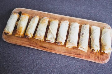 plant-based food, vegan homemade spring rolls with stir fried vegetables filling on cutting board