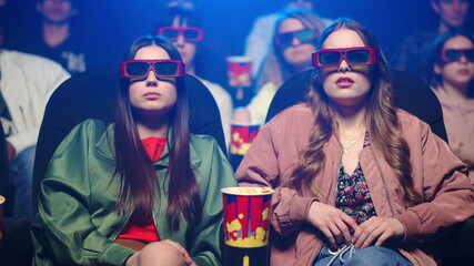 Frightened women jumping in movie theater. Scared girls gesticulating in cinema.