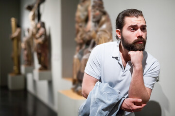 Man looking at stone architectural elements in historical museum hall. High quality photo