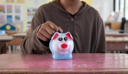person putting coin into piggy bank