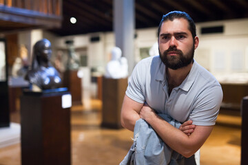 Man looking at stone architectural elements in historical museum hall. High quality photo