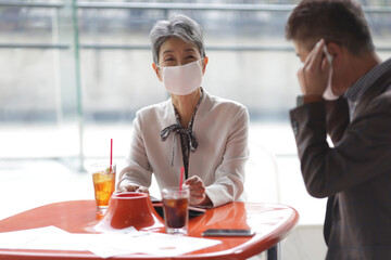 マスクをつけてミーティングをするシニア世代ビジネスマンとビジネスウーマン