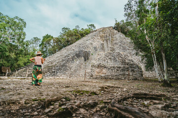 Tourist in the jungle with a backpack and a hat. Tourism in the ancient city Mayan pyramids. Ancient Mayan city in Mexico. Ruins of the city of Coba, Yucatan