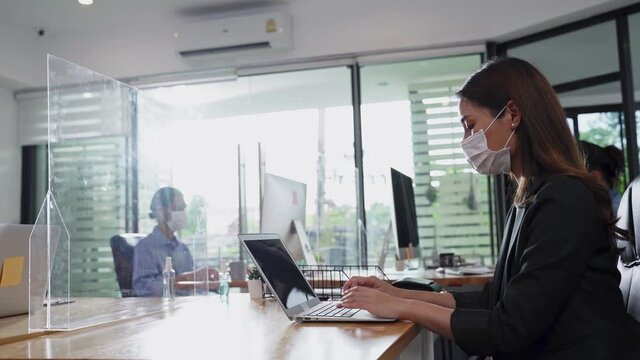 Asian businesswoman wearing face mask working on computer in office