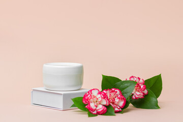 Beauty industry concept. White cosmetic cream jar top with flowers. Side view.  Feminine hygienic skincare product on light pink background. Copy space