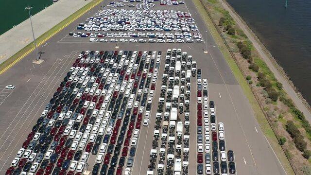 Aerial video of new passenger cars and trucks at a shipping port waiting for import or export