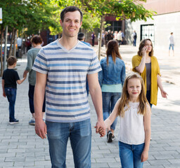 .Young dad walking by the hand with smiling girl on weekend