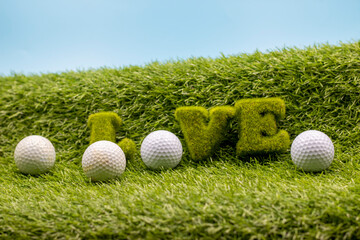 Golf ball with Love word on green grass with blue sky background