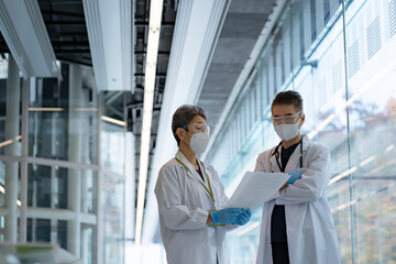 マスクと医療用ゴーグルをつけて打ち合わせをするシニア世代の日本人医師2人