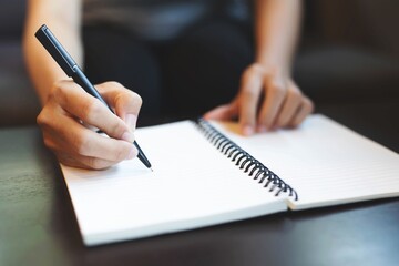 Close up image of young business woman writes with a pen in diary notepad, business and education concept.