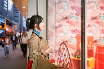 young asian woman shopper standing in front of shop window - obrazy, fototapety, plakaty