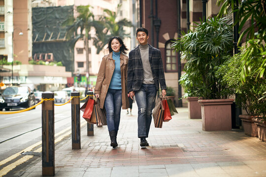 happy young asian couple walking shopping on street