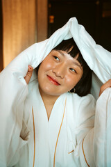 Short hair woman playing with white blanket in bedroom.