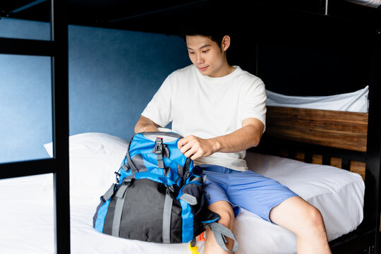 Asian man putting clothes in the bag at hotel before check out.